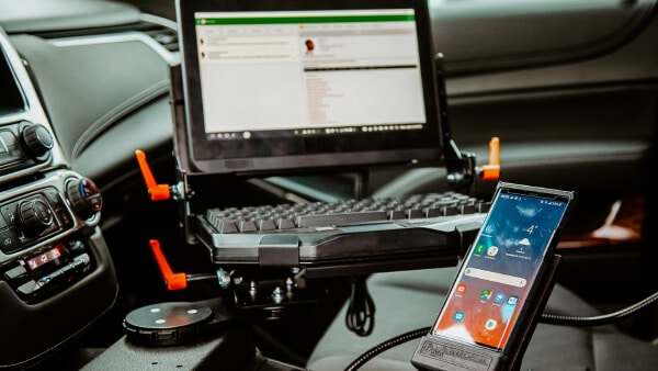 A vehicle’s front seat interior serves as a mobile office setup, featuring a mounted laptop displaying an email screen—ideal for municipal government professionals or teams using managed IT services on the go.