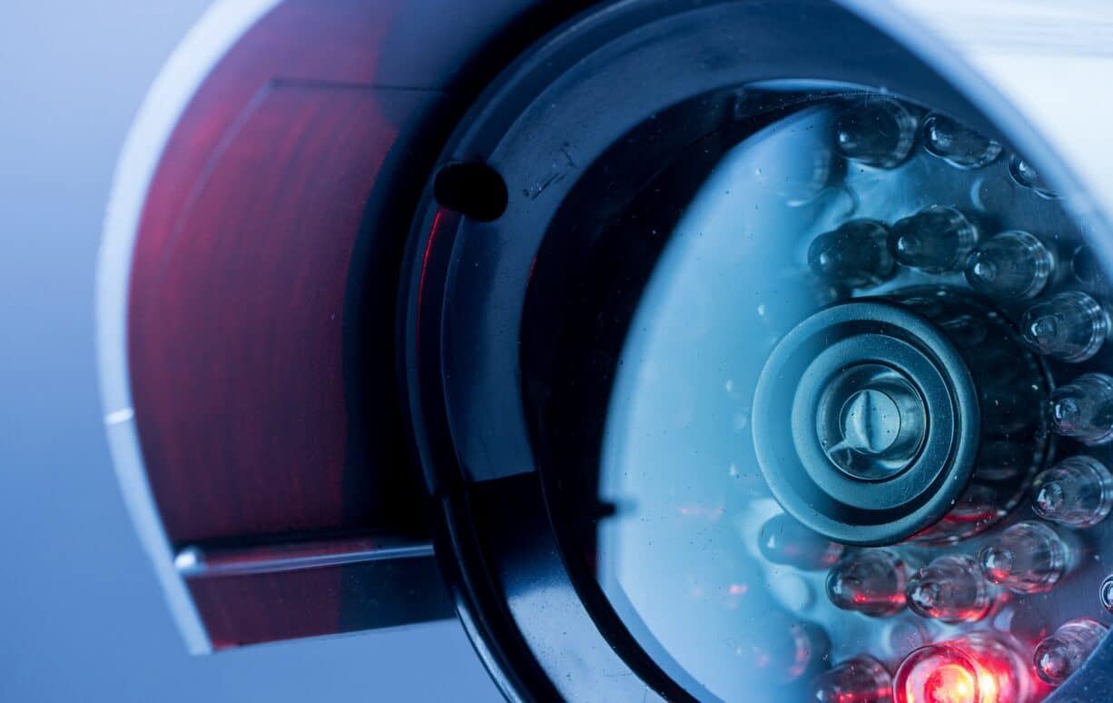 Close-up of a security camera with a glowing red indicator light, metallic housing, and visible lens, set against a blue-toned background—ideal for modern law enforcement technology in Northwestern Ontario.
